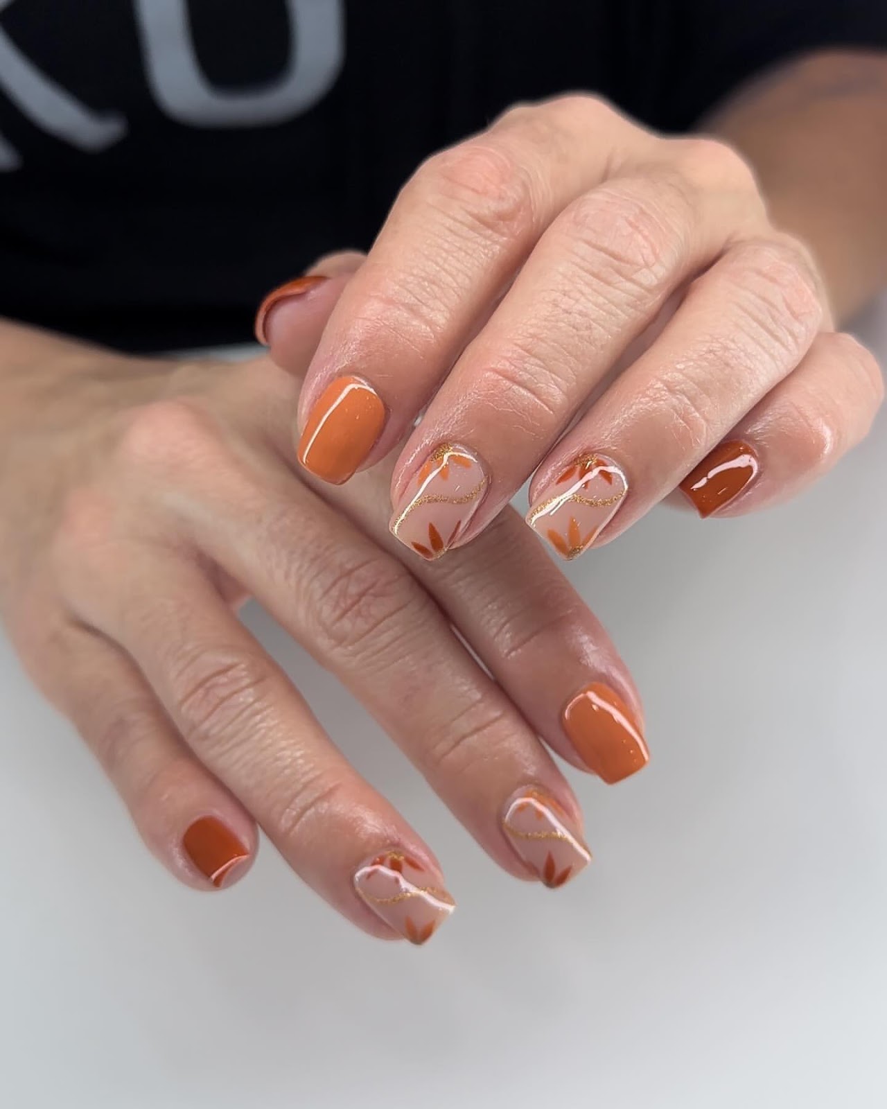 Close-up of hands with fall nail design having Minimalist Leaf Accents