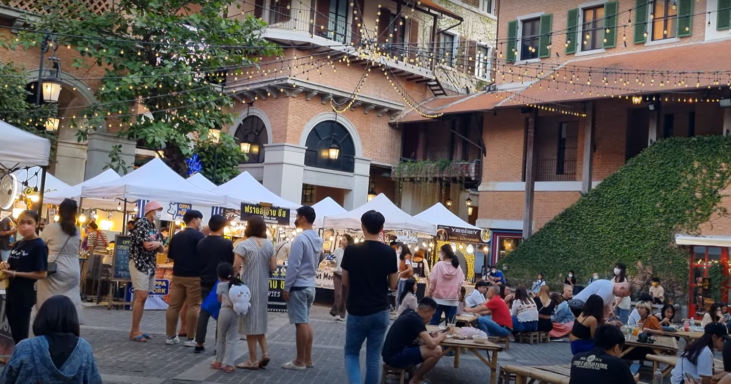 People in a courtyard with tents and trees

Description automatically generated