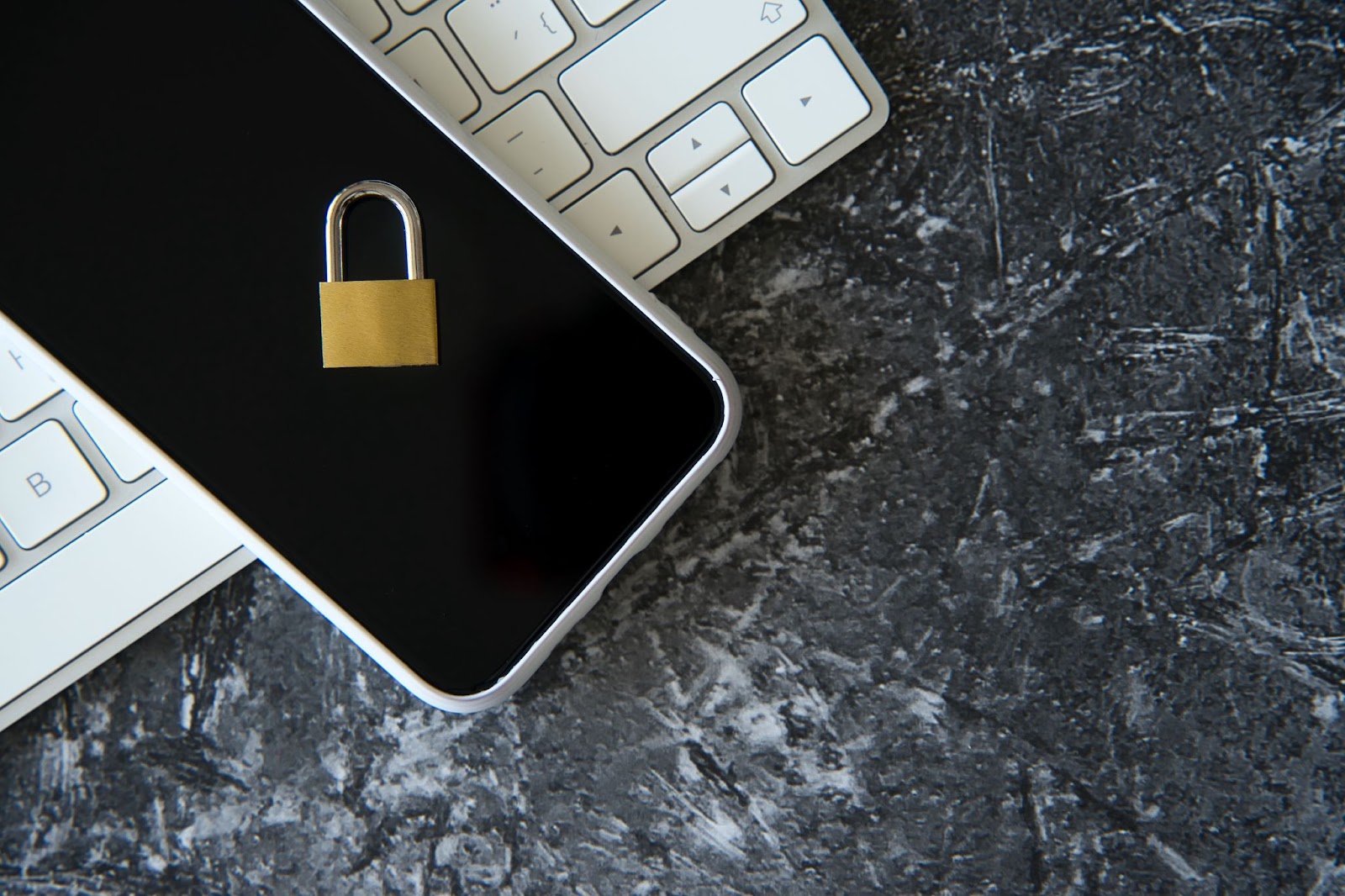 A small golden padlock placed on a smartphone atop a white keyboard, symbolizing secure API calls and robust data privacy. 