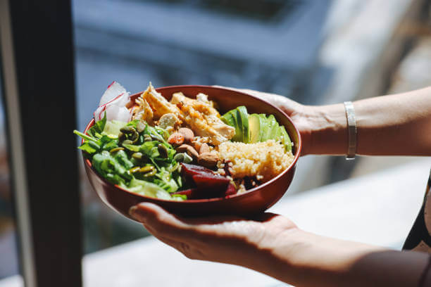 A person holding a bowl of detox-friendly food, perfect for a 7-day cleanse.