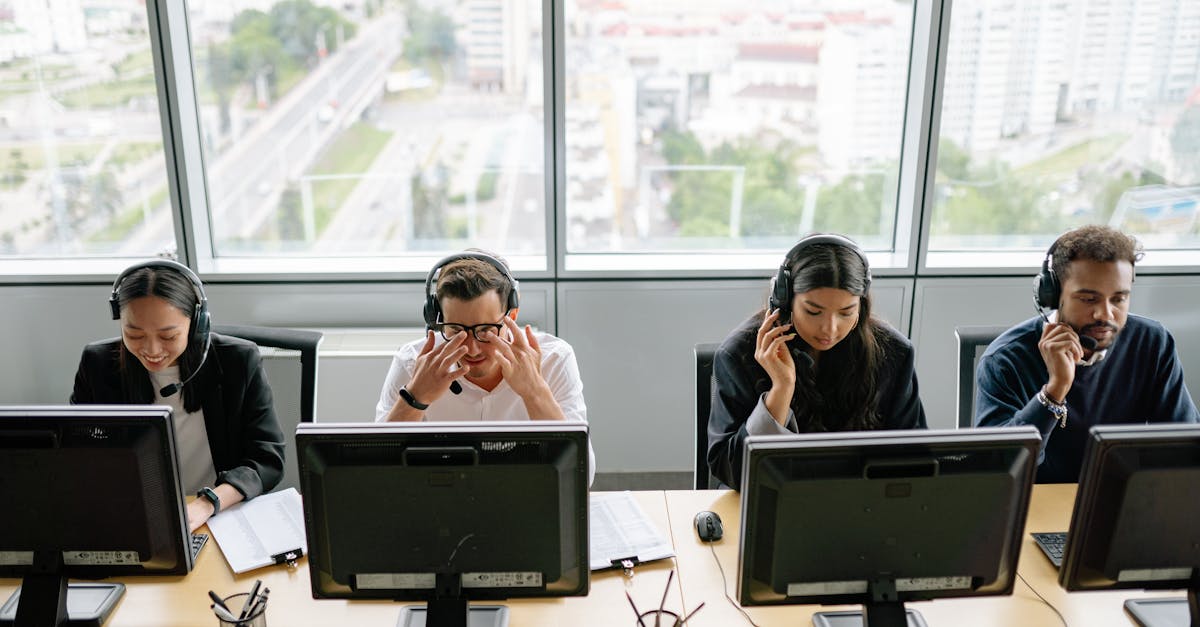 Group of diverse call center employees working at computers in a modern office setting.