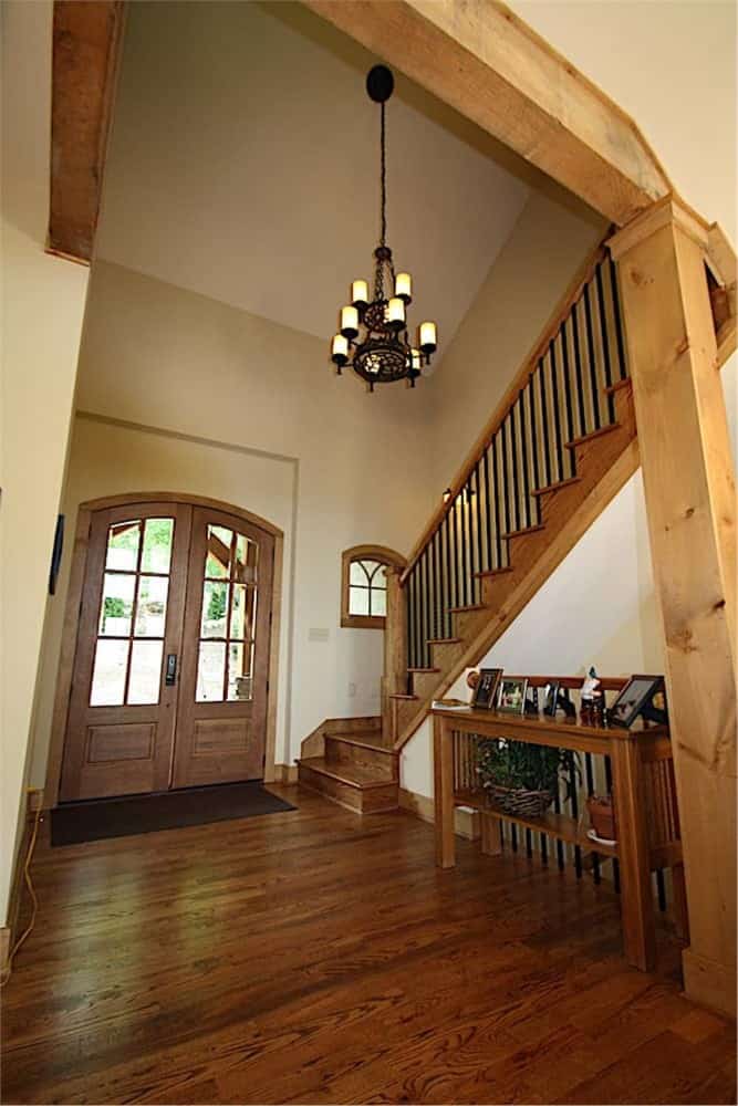Foyer with a french entry door and a wooden console table placed against the traditional staircase.