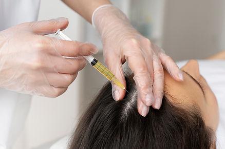 A surgeon is injecting syringe on female scalp