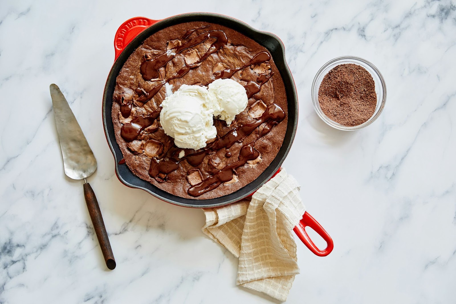 Cookie baked in a large skillet topped with ice cream and chocolate fudge