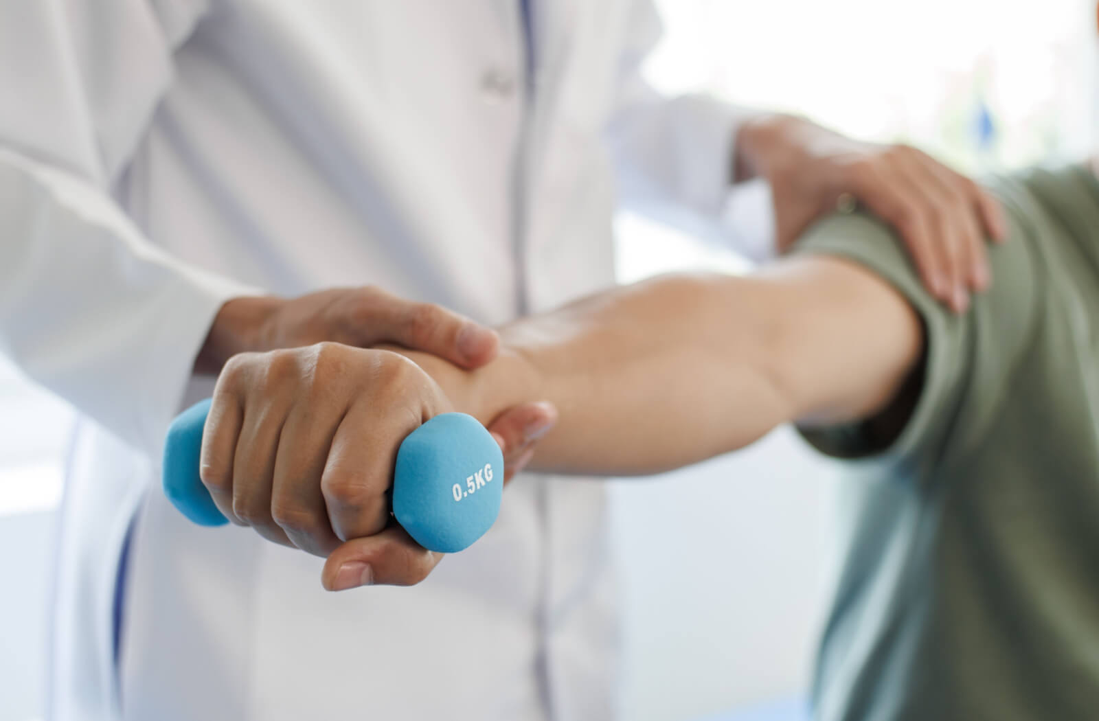 A caregiver in memory care helping an older adult with Parkinson's use a small blue weight during an exercise as part of their care plan