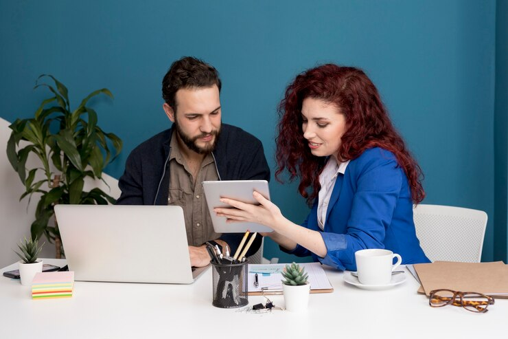 Two people discussing good feature article topics on a laptop and tablet