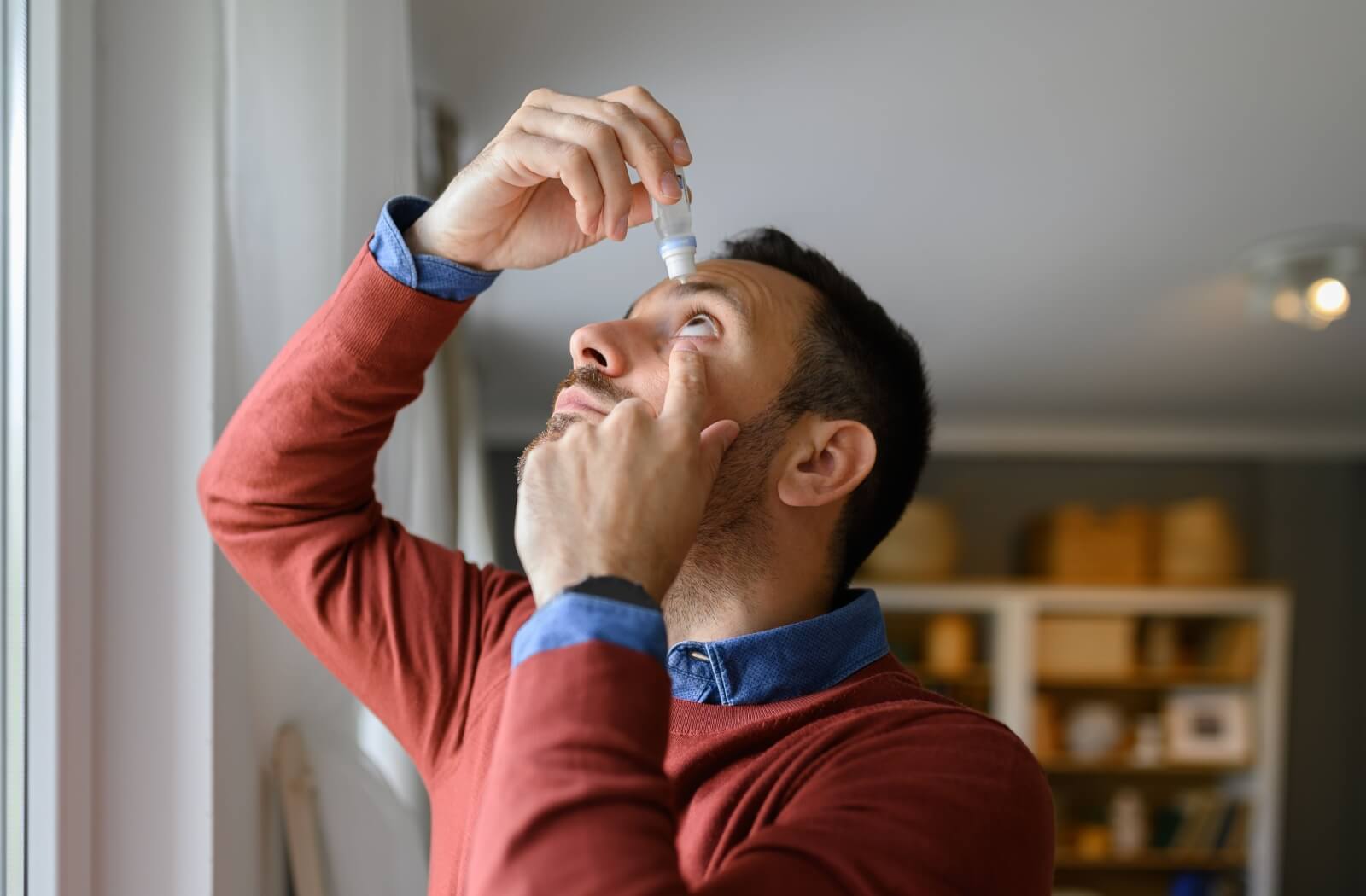 A person with dry eyes puts eyedrops in to relieve their symptoms and prevent blurry vision.