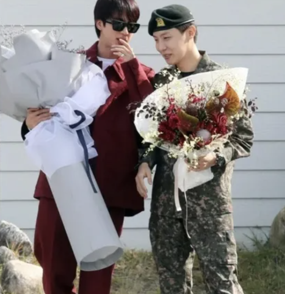 This may contain of BTS's J-Hope and BTS member Jin holding flower