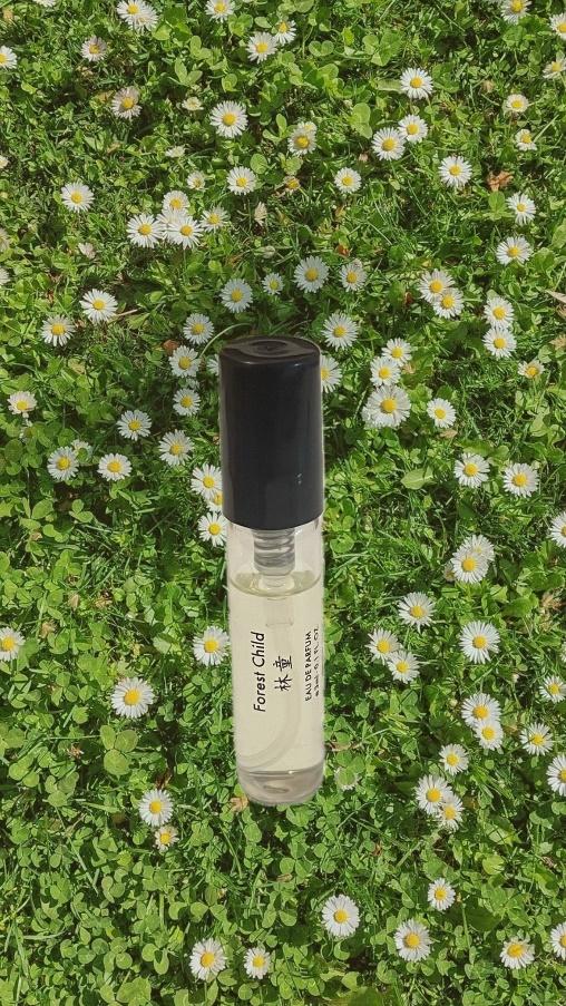 A small bottle of perfume in a field of flowers

Description automatically generated