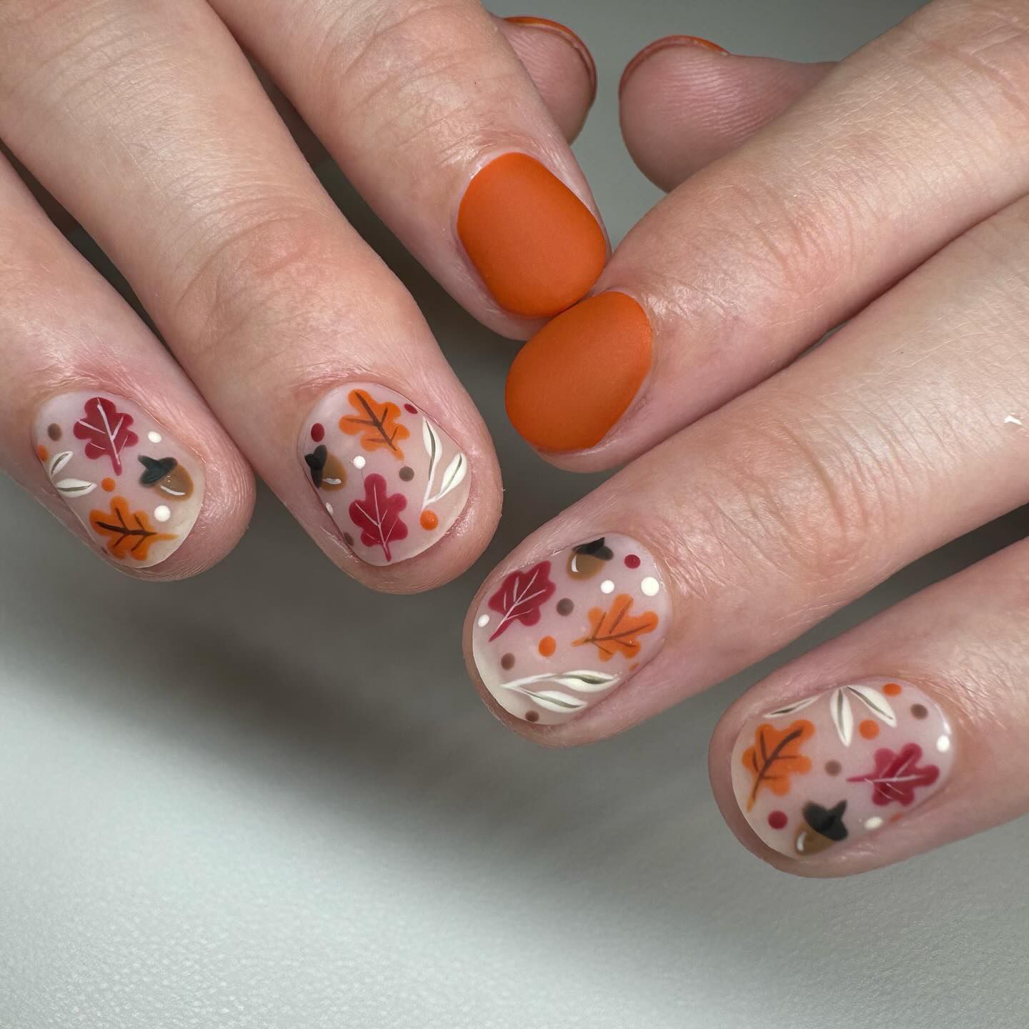 Close-up of hands with fall nail design having Falling Leaves Motifs