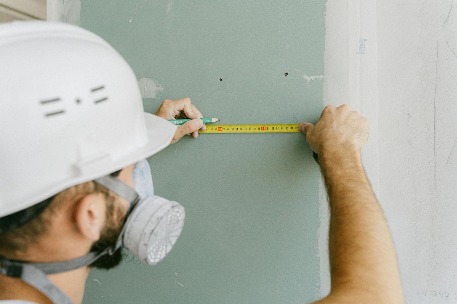 Person installing a wall panel using tools, demonstrating a step in the DIY TV wall project.