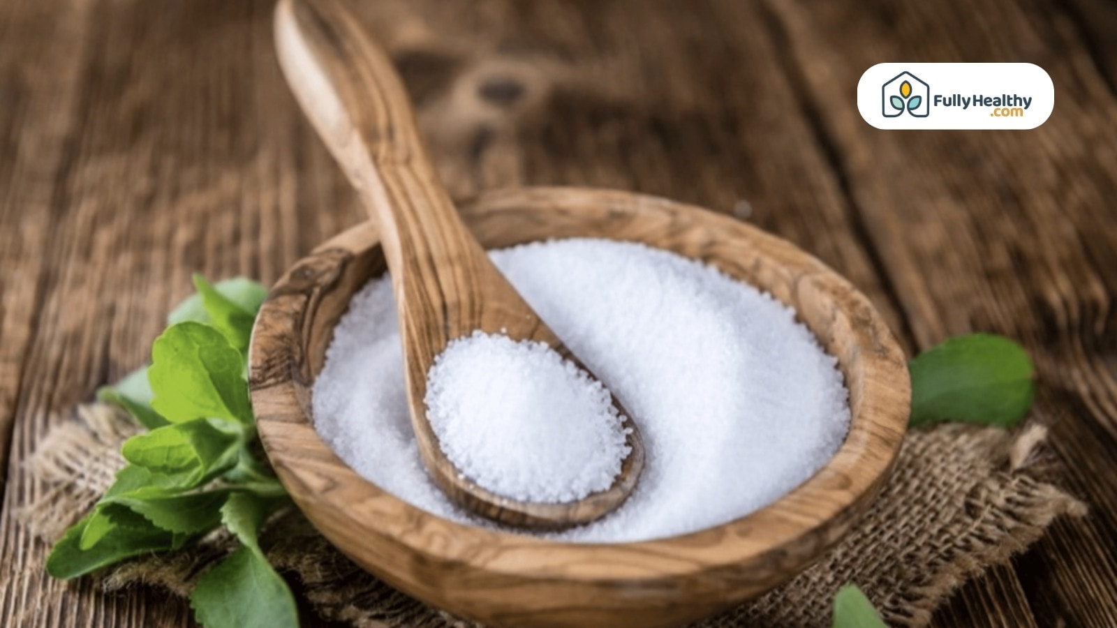 Wooden bowl of stevia sweetener with green stevia leaves nearby