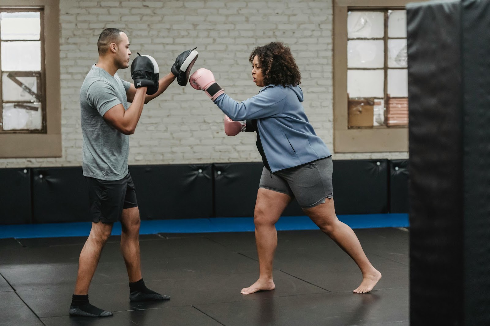 A lady practicing boxing moves with her instructor in a training studio