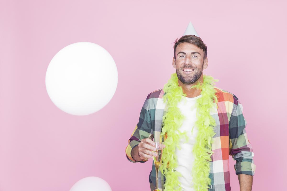 A man holding a glass of wine while posing for a photo
