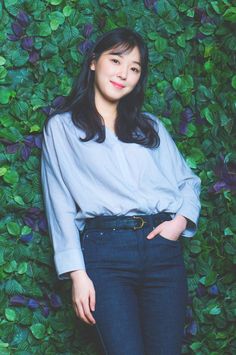 This contain Jo Woo Ri standing in front of a green wall with her hands on her hips and looking at the camera