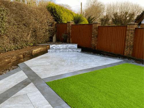 Clean backyard design featuring artificial grass front yard ideas paired with modern stone tiles and wooden fencing.