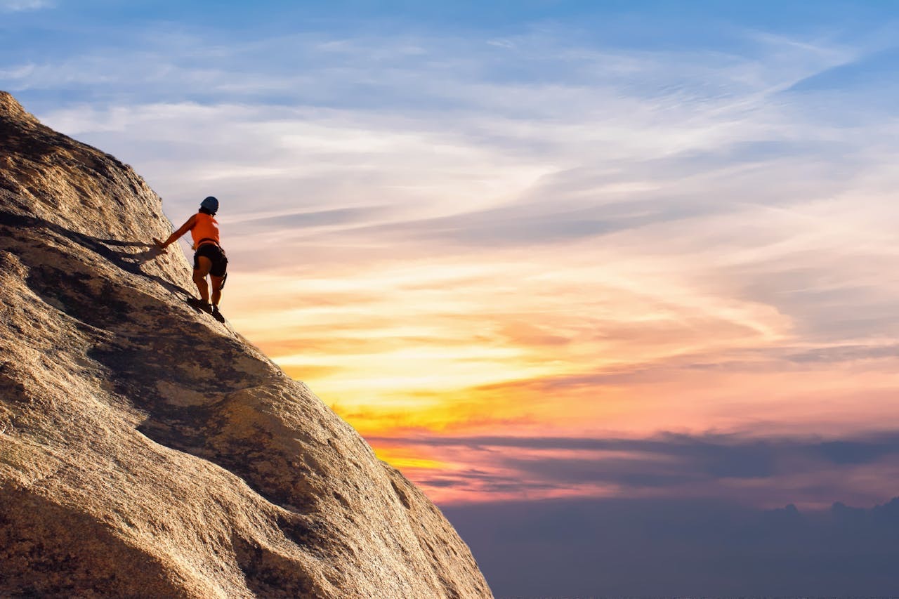 Person climbing a mountain with a sunset in the background // Healthier Veterans Today