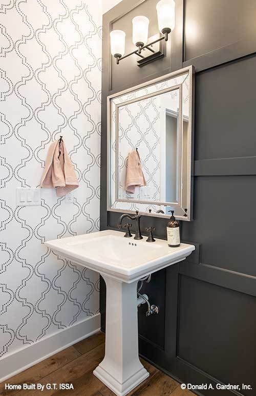 Powder room with a pedestal sink paired with a chrome framed mirror and glass sconces.