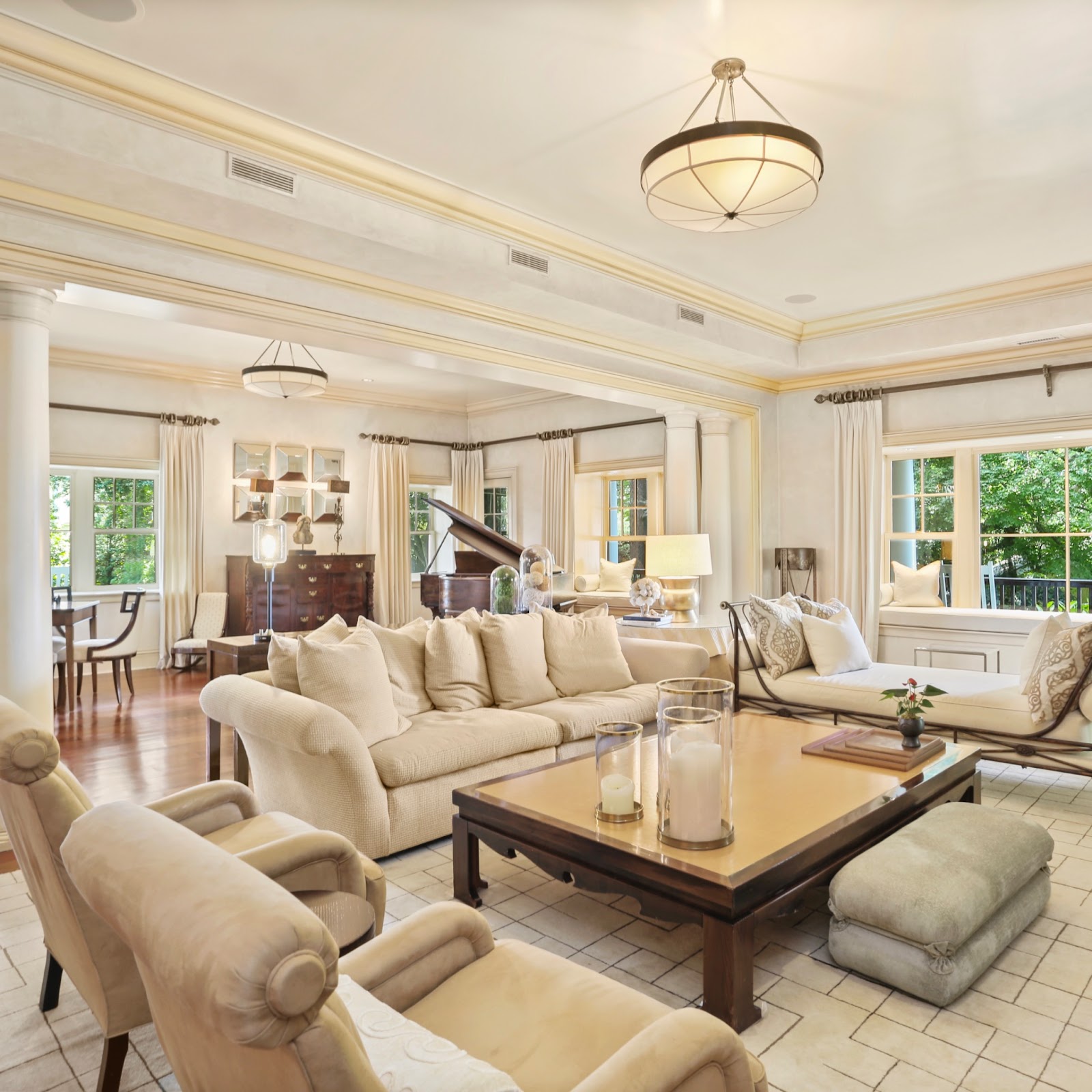A warm creamy white living room features large picture windows with a lot of natural light.