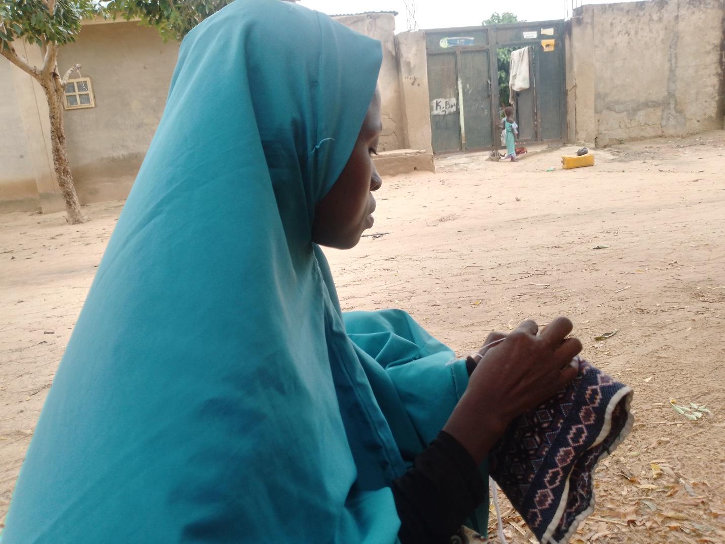 Jamila Mohammed, 36, weaving a cap while narrating her experience at Jiddari Clinic. (Image Source: Rukaiyatu Idris)