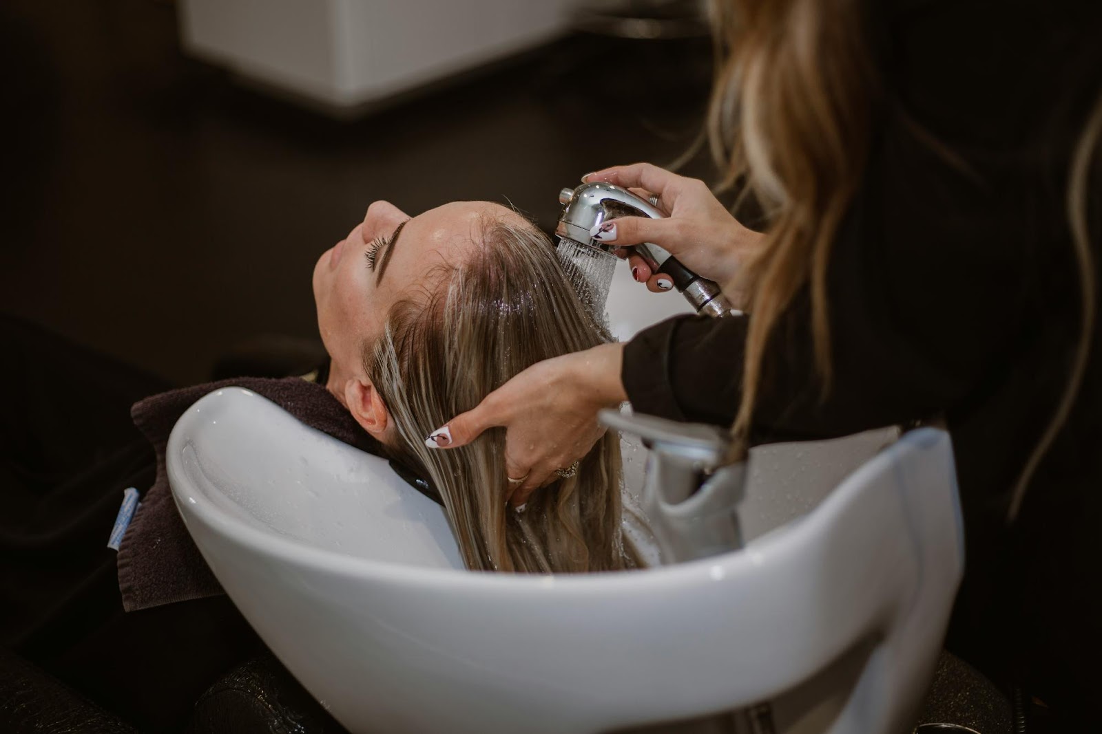 Client getting hair washed at salon before clip-in extension application