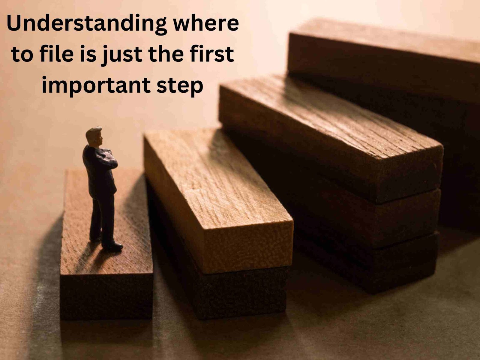 A miniature figure stands on stacked wooden blocks, with more blocks nearby. Text reads: "Understanding where to file is just the first important step.