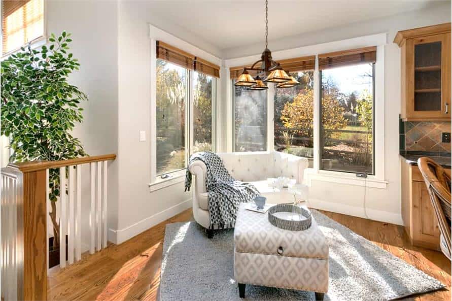 The sitting area is furnished with a white tufted seat and a patterned ottoman over a gray plush rug.