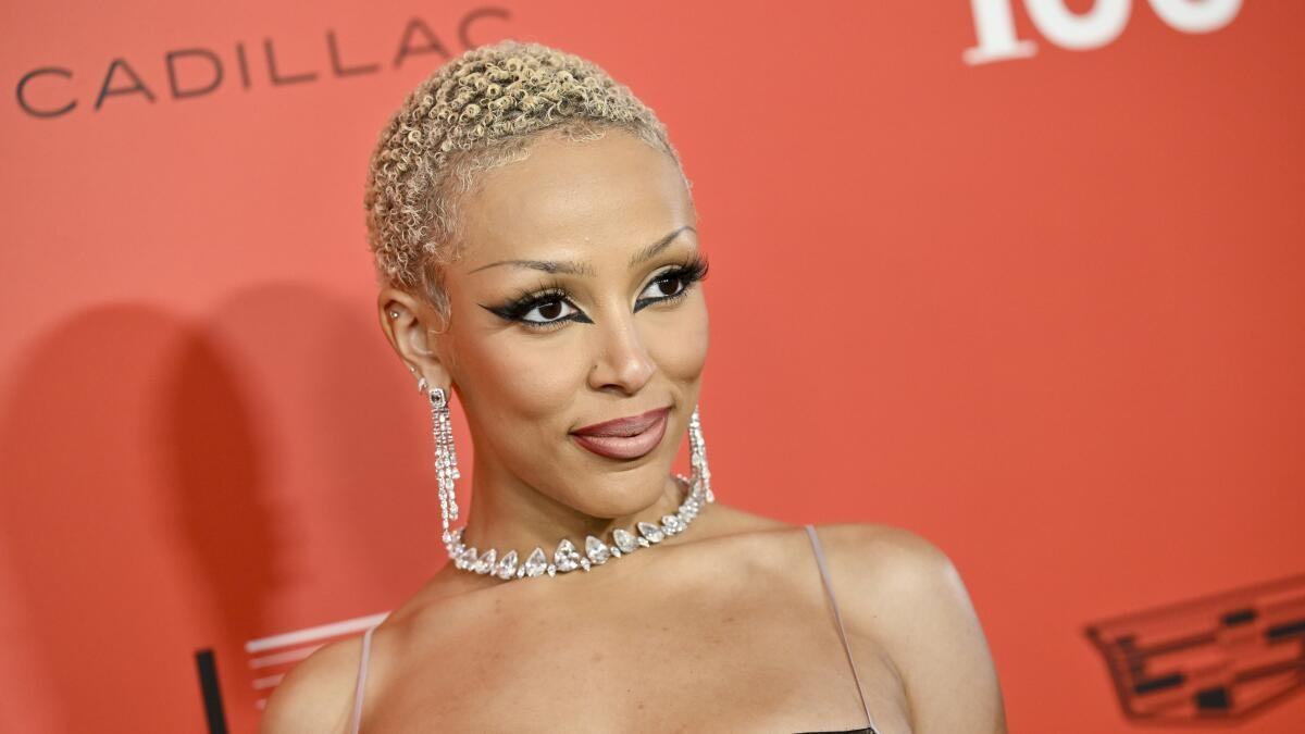 A person with short blonde hair and diamond earrings

AI-generated content may be incorrect.