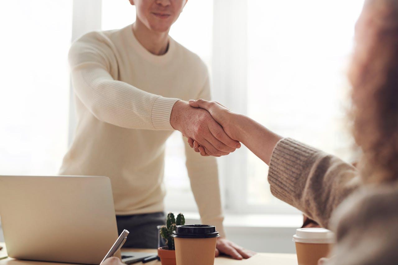  A man shaking a woman’s hand across the table