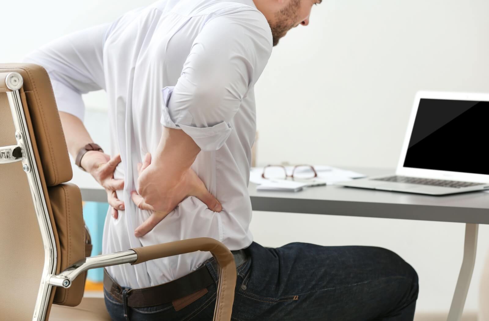 An office worker stretches their sore back after hours of bad posture.