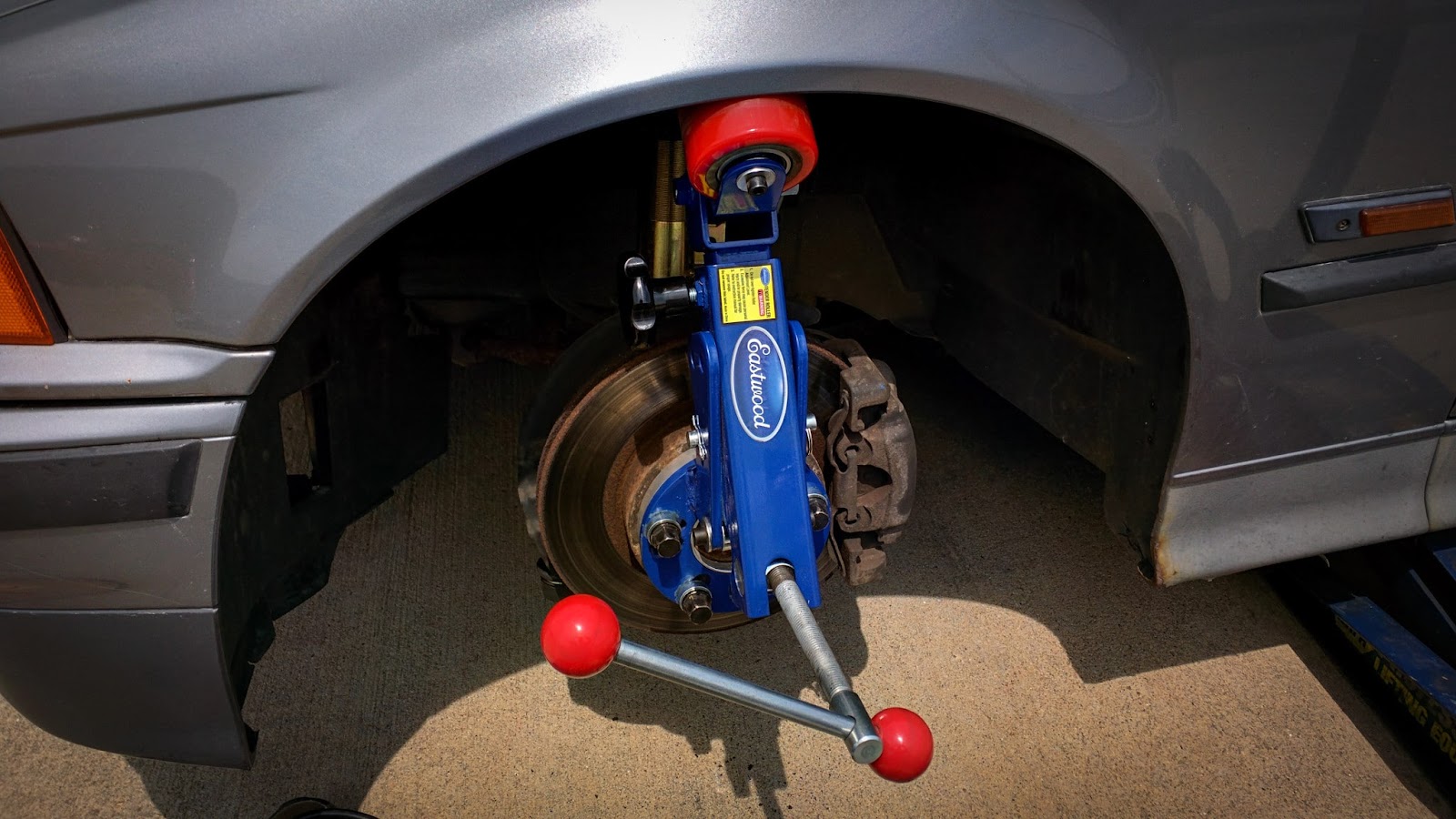 Image showing a fender roller tool correctly positioned on a car's wheel hub