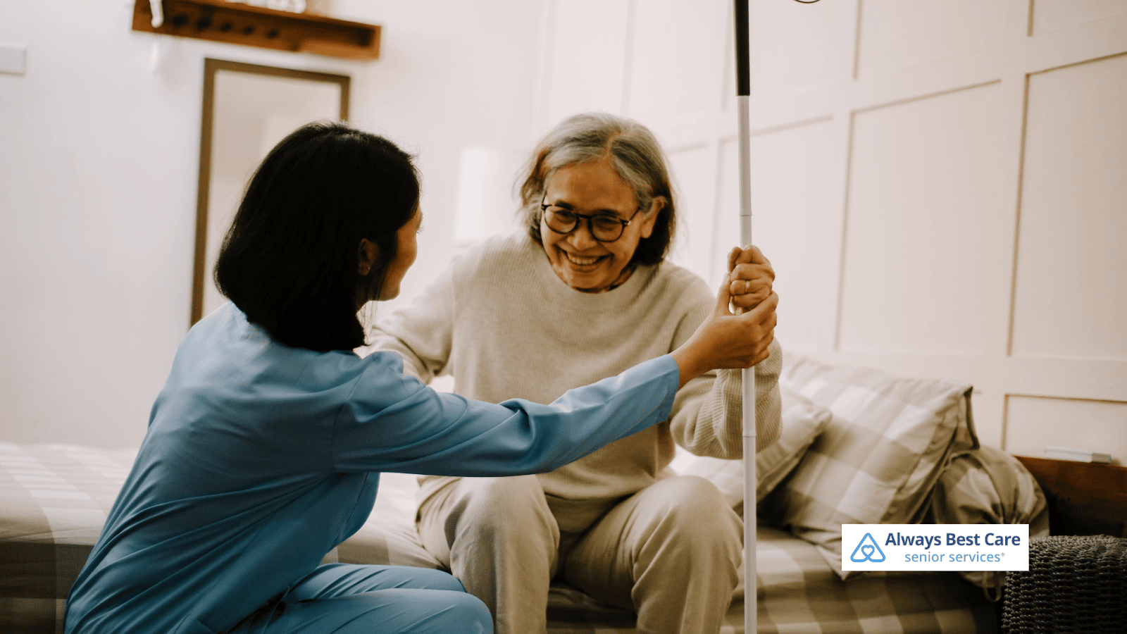 This image depicts a caregiver helping a senior woman stand up