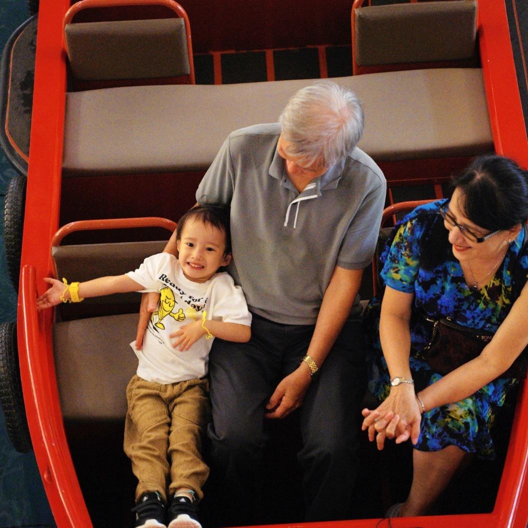 A person and person sitting on a small child on a ride

Description automatically generated