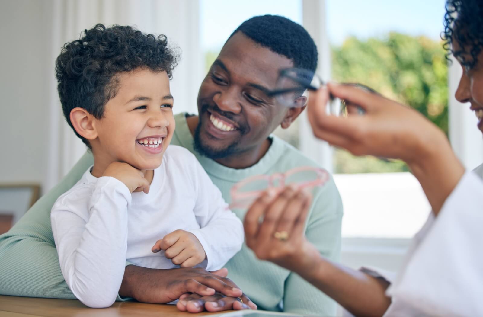  A child, father, and optometrist smile in an optometry office, selecting a pair of glasses.