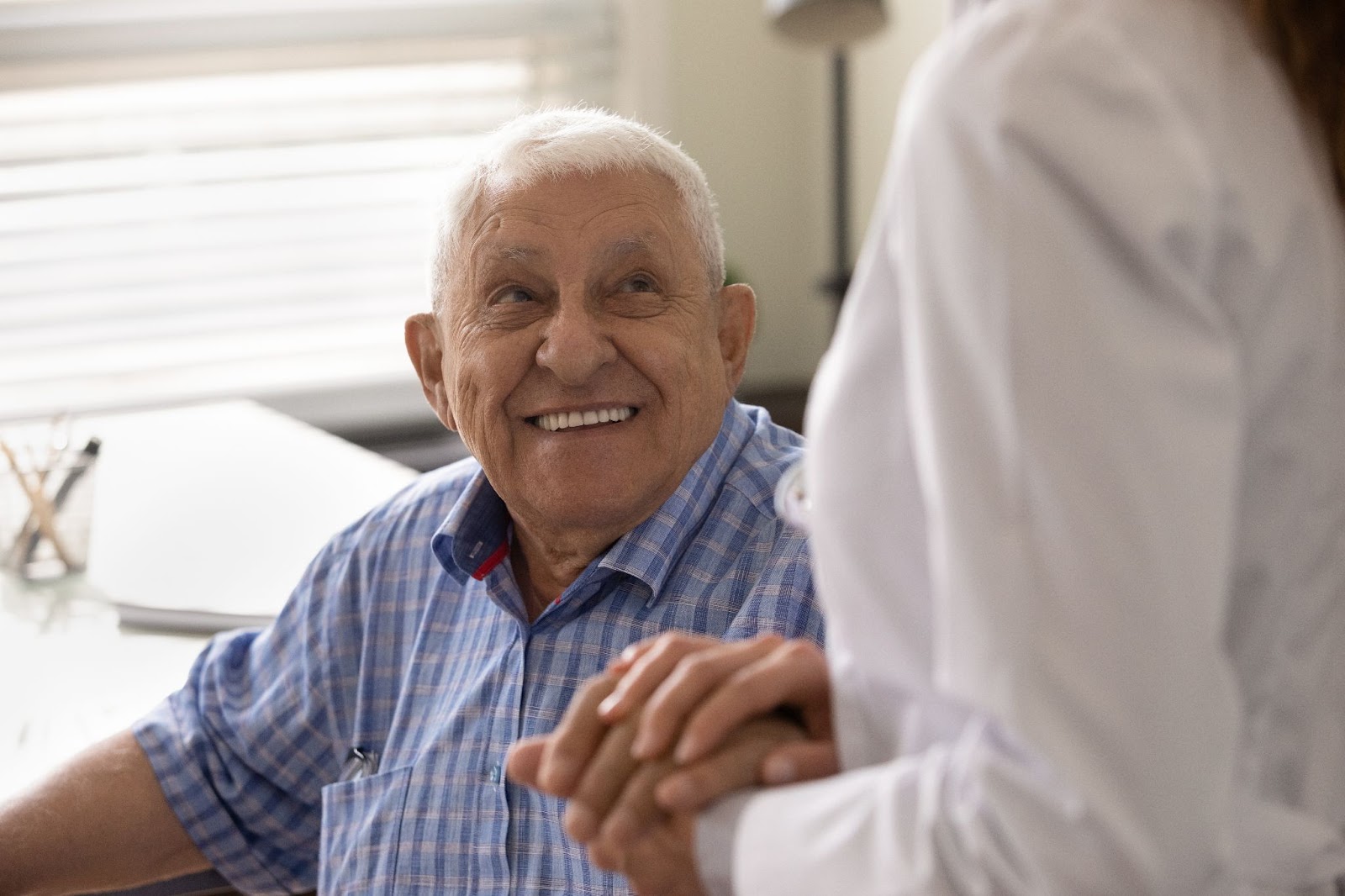 A smiling senior man holds his daughter's hand while communicating.