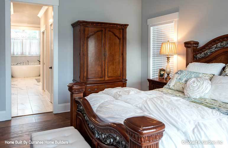 Primary bedroom with wooden furnishings and walk-in closets leading to the private bath.