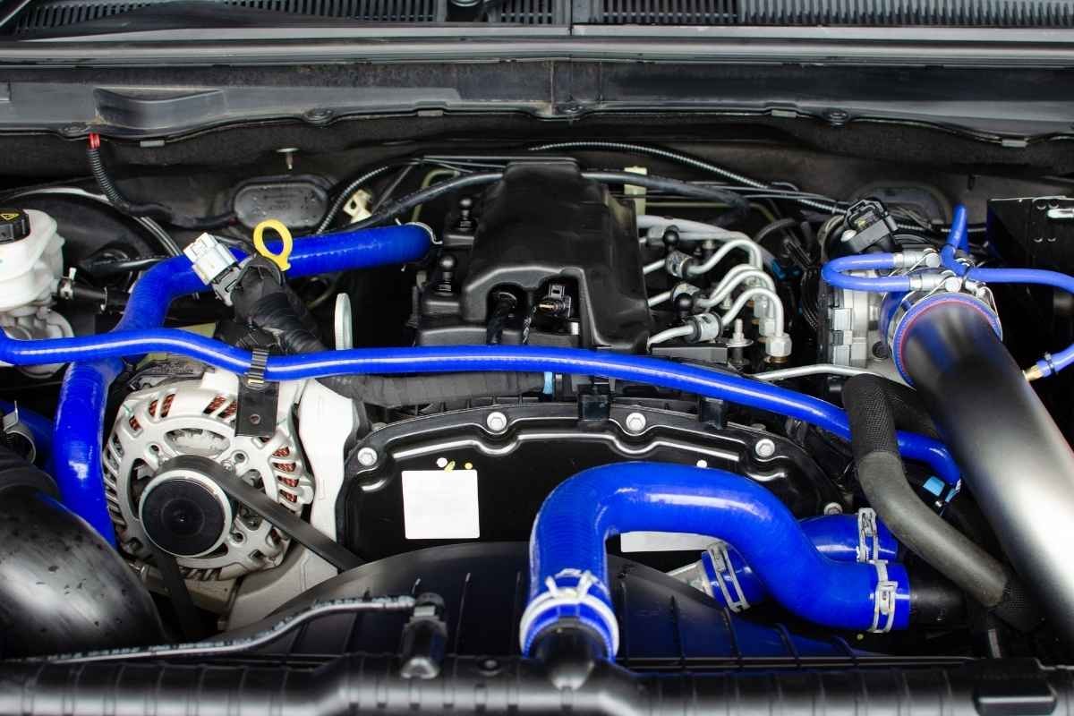 Engine bay with blue aftermarket radiator and coolant hoses, alternator, and intake components visible.