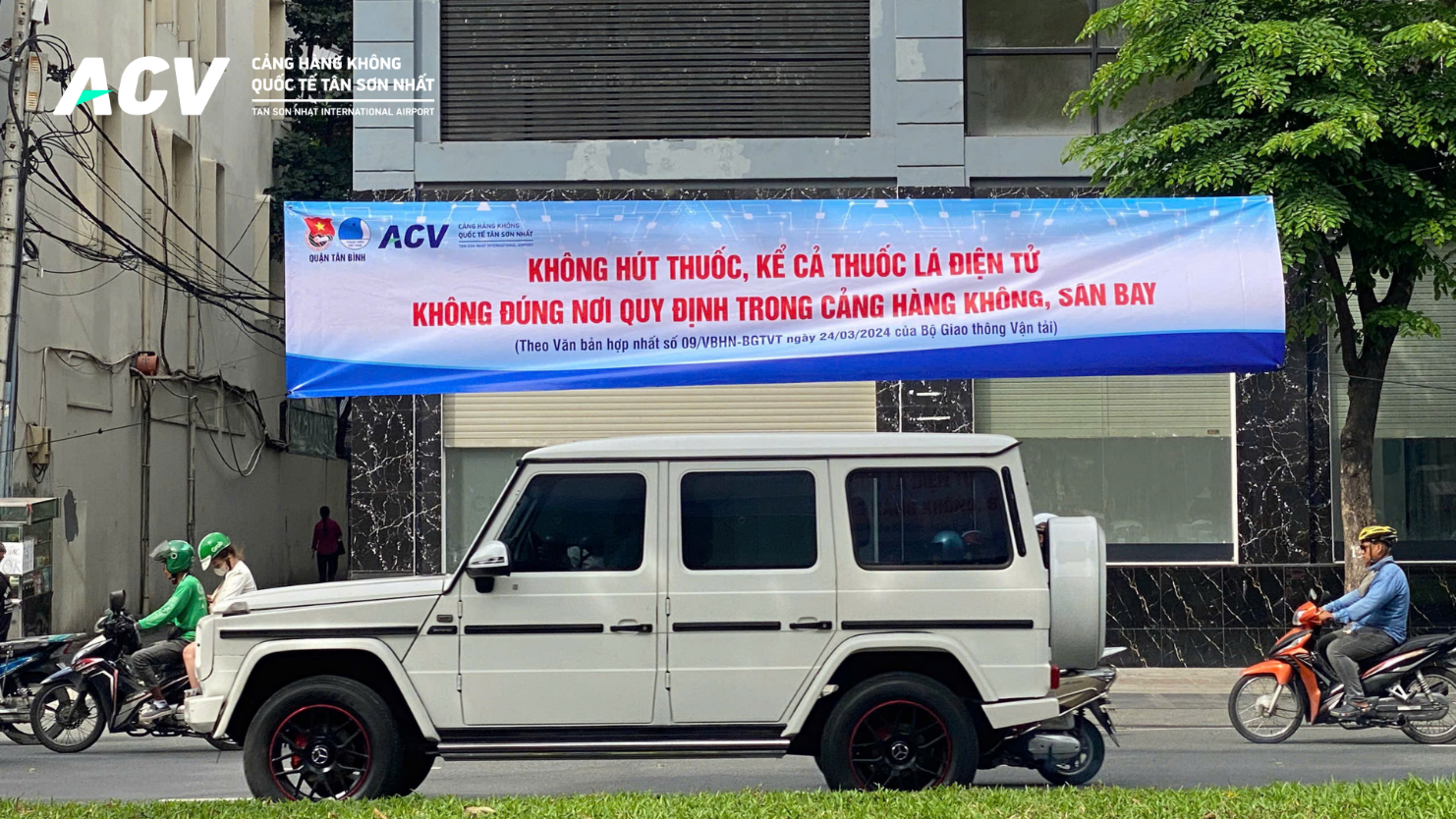 A white car on the street under a bannerDescription automatically generated