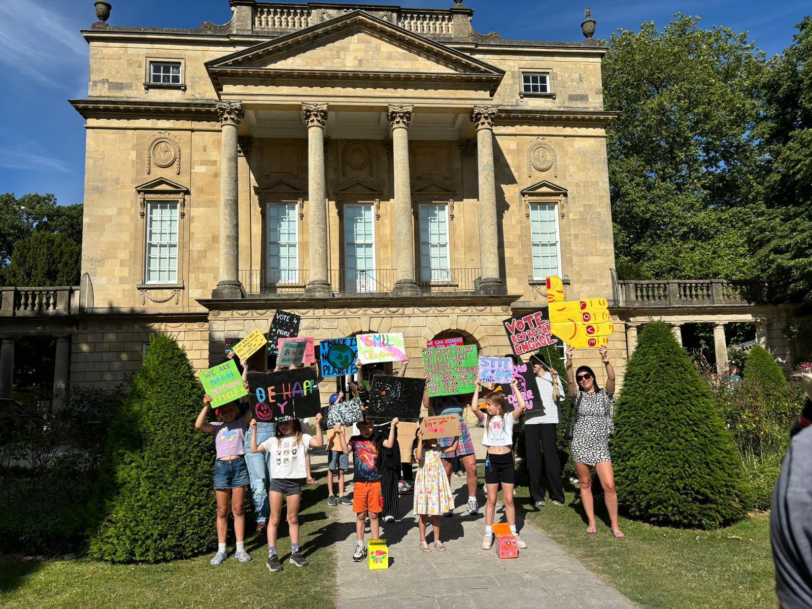 A group of people holding signs in front of a building

Description automatically generated