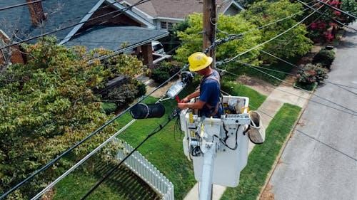 Free Electrician in a bucket lift repairing power lines from a utility pole in a suburban neighborhood. Stock Photo