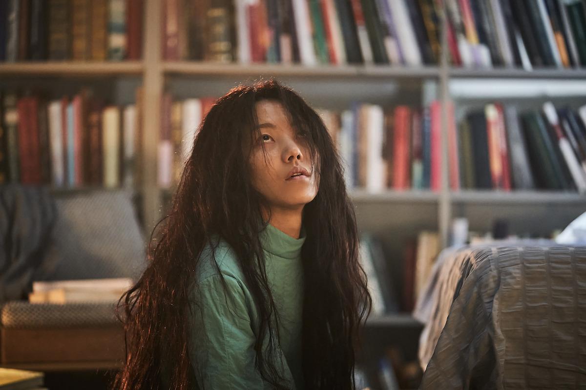 Kim Shin-rock as Park Jungja sits on a living room floor while looking up toward the ceiling in an image from ‘Hellbound’ Season 2.