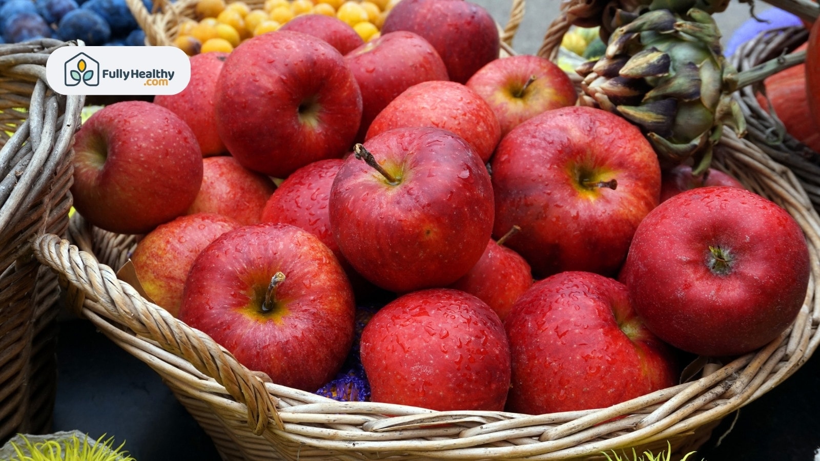 Fresh red apples in a basket with droplets of water