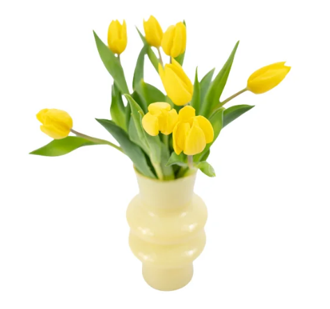 Tulipas amarelas com as folhas verdes em um vaso arredondado abstrato também amarelo com o fundo branco.