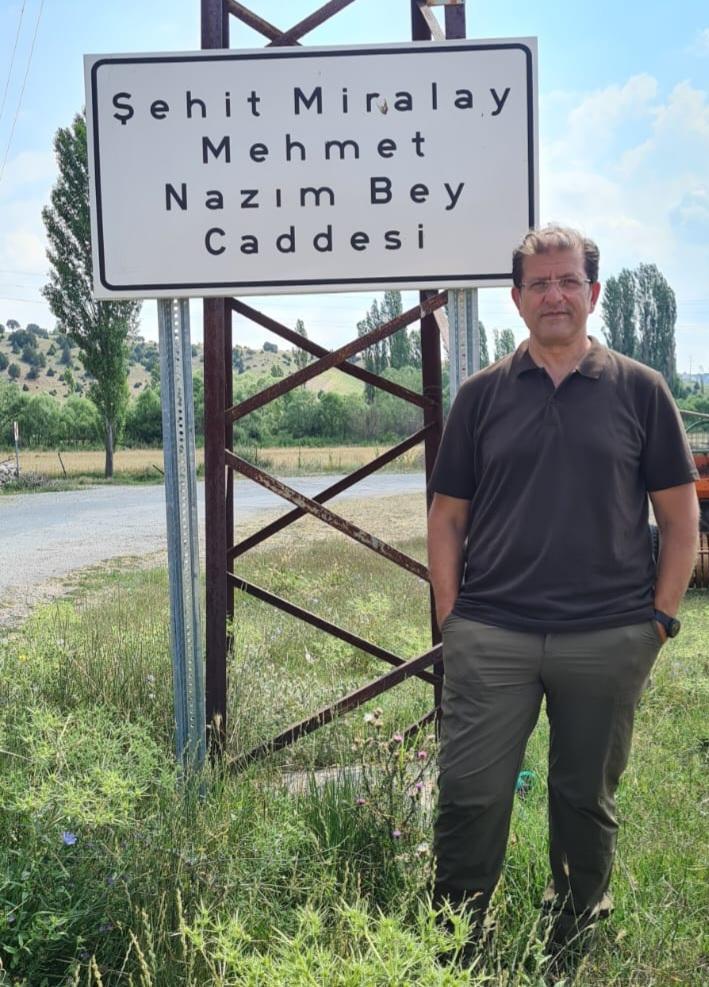 A person standing in front of a sign

Description automatically generated