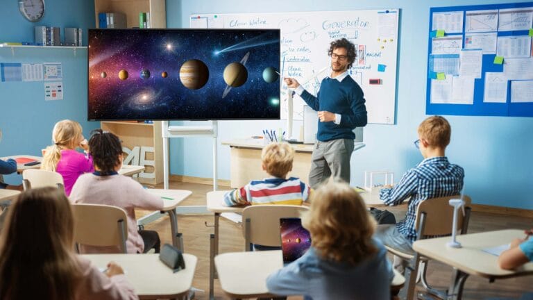 A teacher using an interactive video screen to teach young students about  planets