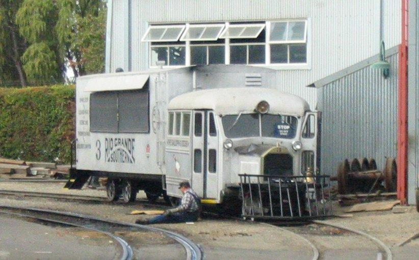 A person sitting on the ground next to a white train

Description automatically generated