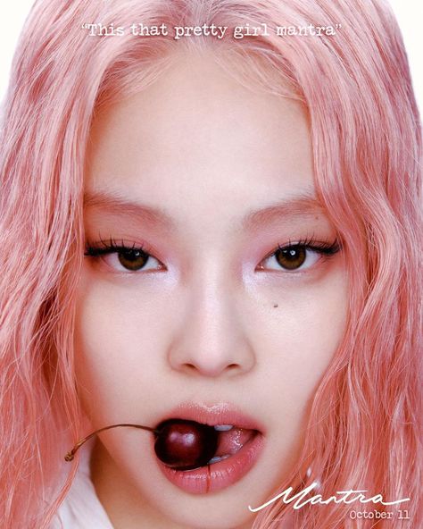 A picture of BLACKPINK Jennie on a pink hair and a fruit in her moth 