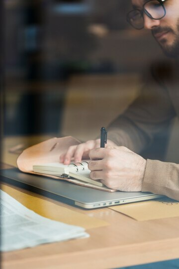 A man writing down something in a notebook