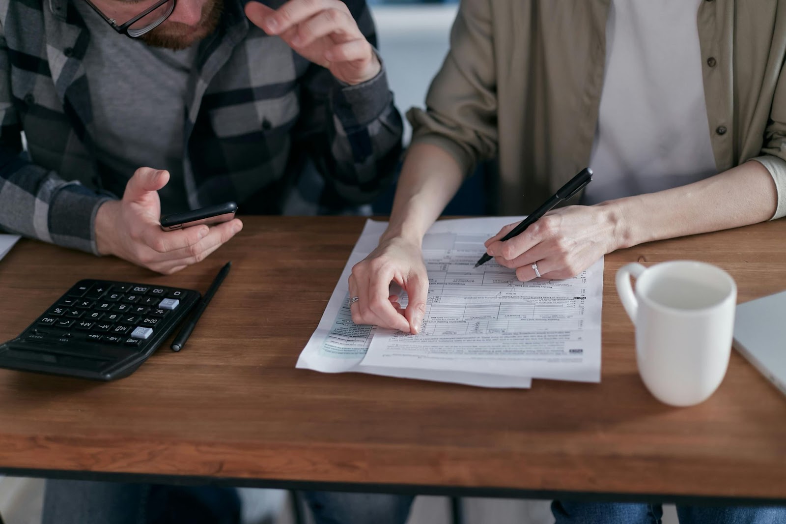 Couple reviewing financial documents with calculator and smartphone on the table