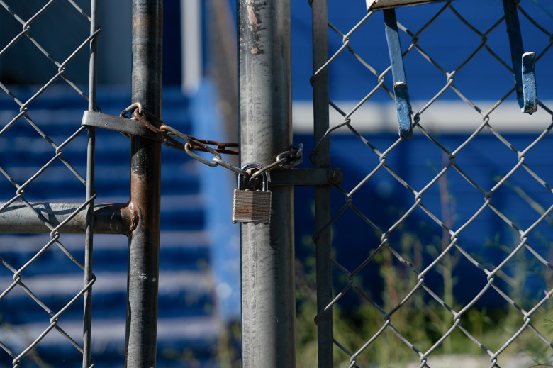 A chained lock on the wired gate in front of iconic Warriors House, formerly painted blue and yellow to honor the Golden State Warriors, in Oakland on July 22, 2024. The house was previously a community land trust property. Photo by Florence Middleton, CalMatters